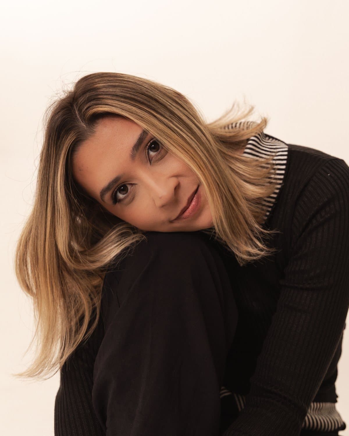Izabela Oliveira, psicóloga clínica especialista em Terapia Cognitivo-Comportamental, com a cabeça apoiada sobre o joelho