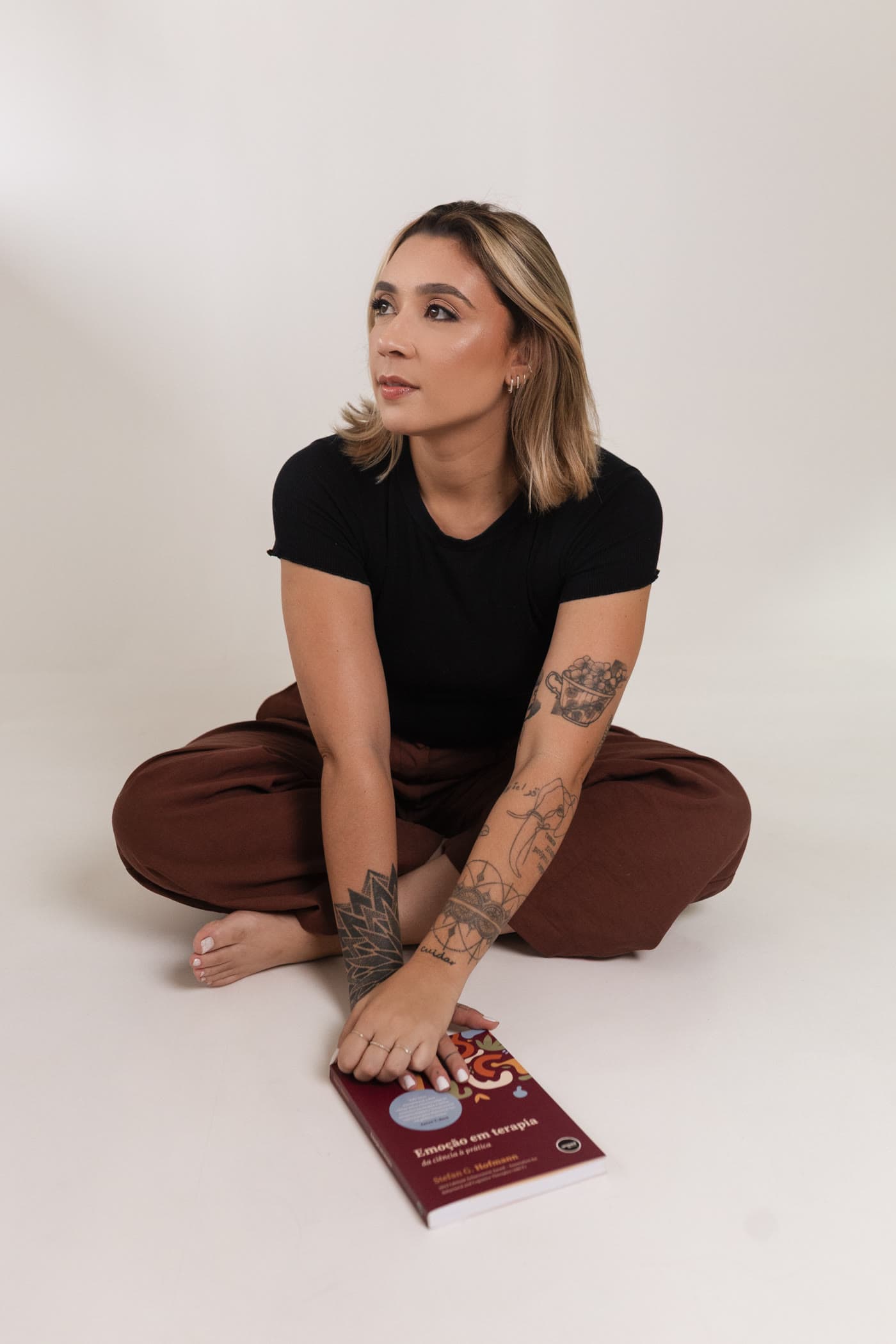 Izabela Oliveira, neuropsicóloga em Belo Horizonte, sentada no chão com o livro Emoção em terapia